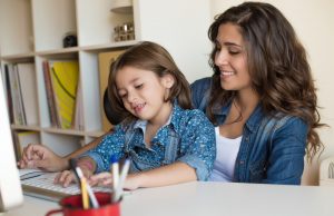 alt="Young woman with little girl using computer at home, self isolating"