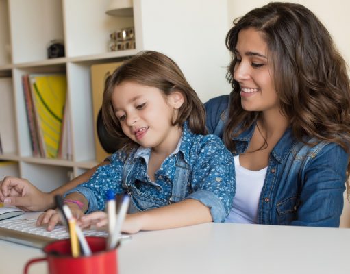 alt="Young woman with little girl using computer at home, self isolating"