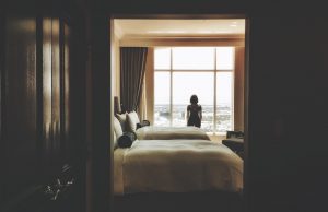 woman standing near window inside bedroom