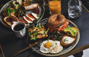 hamburger, fried eggs, avocado slices, and bread on round gray plate