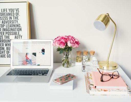 MacBook Air beside gold-colored study lamp and spiral books