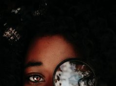 woman placing magnifier on her left eye
