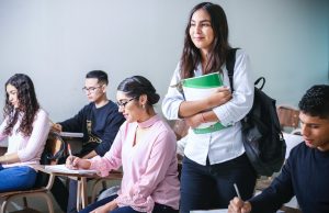 woman carrying white and green textbook