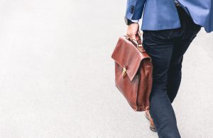 person walking holding brown leather bag