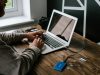 person in gray long sleeve shirt using macbook air on brown wooden table