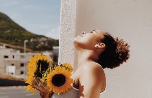 woman holding sunflower in vase