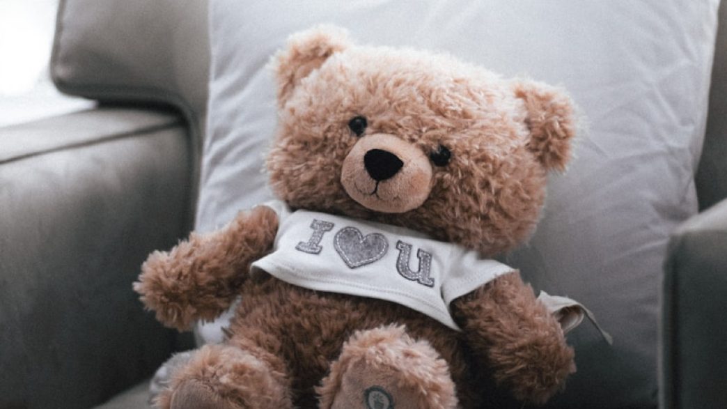 a brown teddy bear sitting on top of a couch