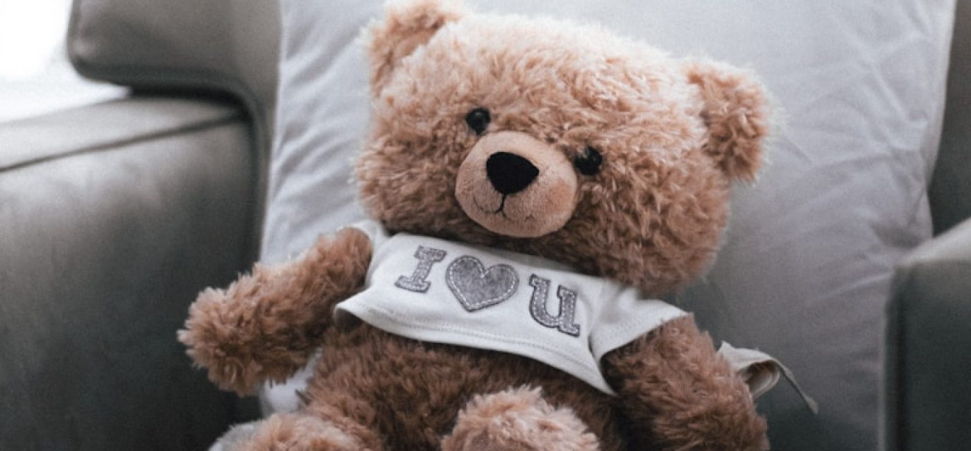 a brown teddy bear sitting on top of a couch