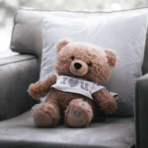 a brown teddy bear sitting on top of a couch