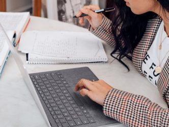 woman in white and black plaid long sleeve shirt using black and silver laptop computer