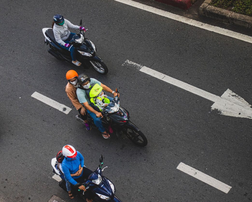 Overhead view of motorcyclists in helmets riding along a city road