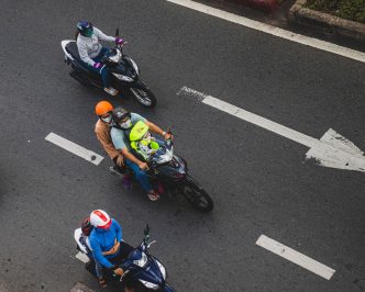 Overhead view of motorcyclists in helmets riding along a city road