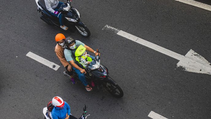 Overhead view of motorcyclists in helmets riding along a city road