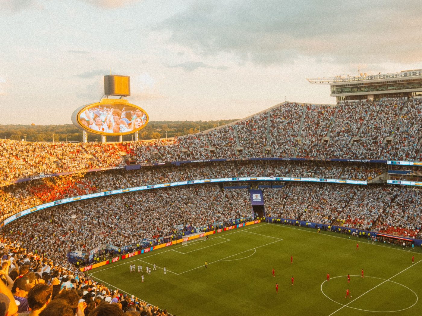 A packed football stadium at sunset during a match