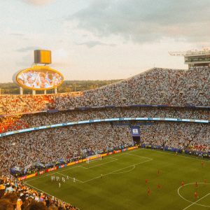 A packed football stadium at sunset during a match