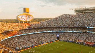 A packed football stadium at sunset during a match