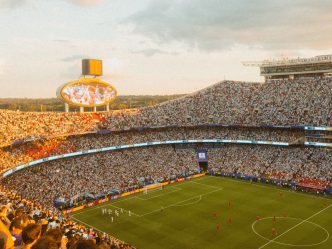 A packed football stadium at sunset during a match