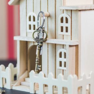 Miniature wooden house with a vintage key, symbolizing real estate and homeownership.