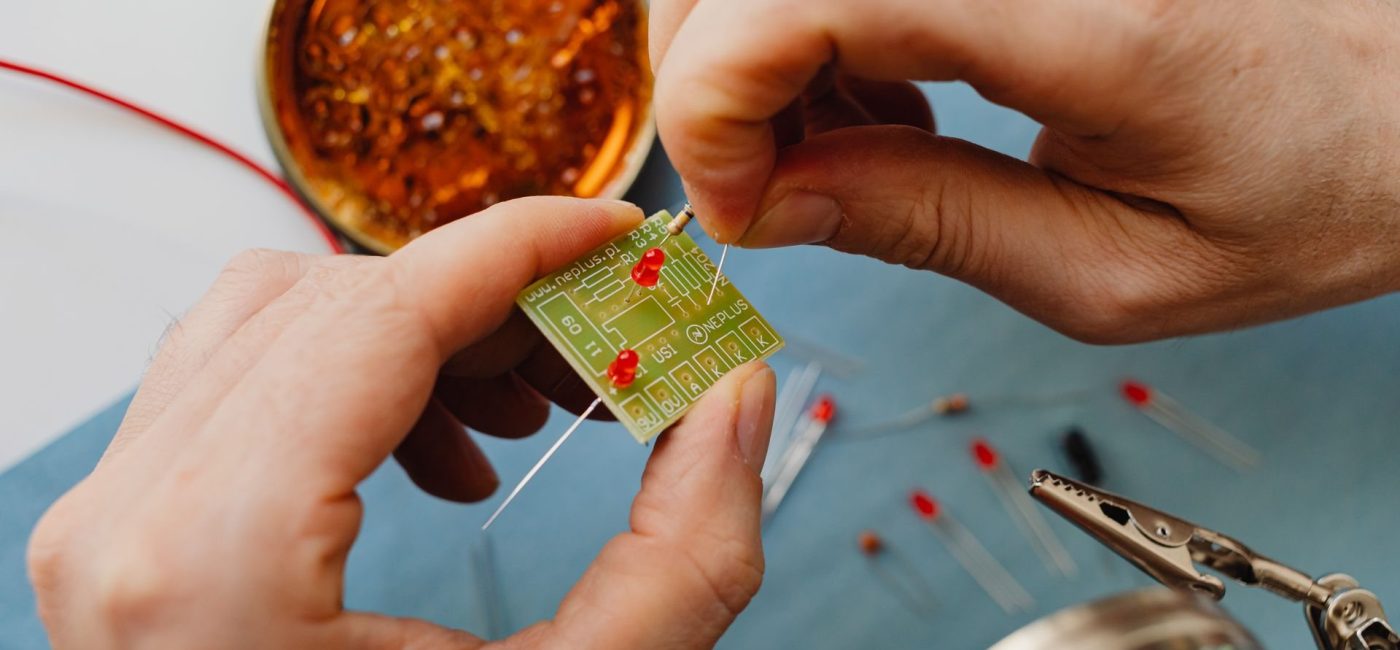 Hands fitting small electronic components onto a printed circuit board