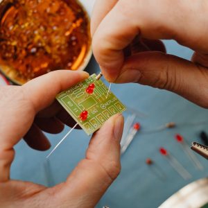 Hands fitting small electronic components onto a printed circuit board