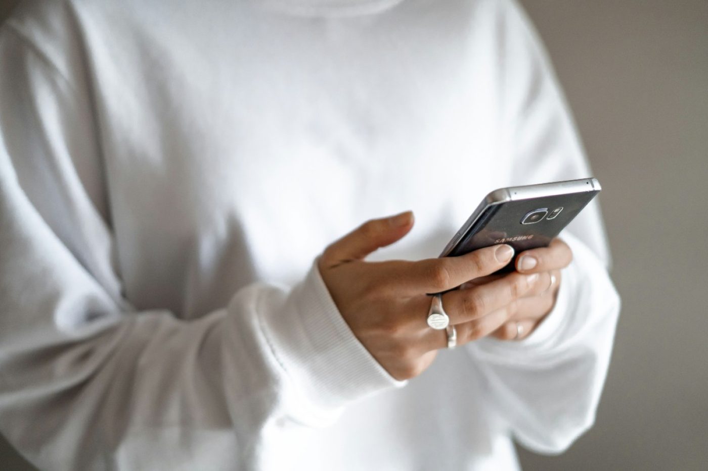 Stressed spending can be tamed with budgets, limits and planned repayments: a person in a white jumper checking their household budget on a mobile phone