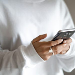 Stressed spending can be tamed with budgets, limits and planned repayments: a person in a white jumper checking their household budget on a mobile phone