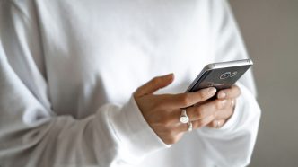 Stressed spending can be tamed with budgets, limits and planned repayments: a person in a white jumper checking their household budget on a mobile phone