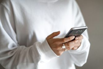 Stressed spending can be tamed with budgets, limits and planned repayments: a person in a white jumper checking their household budget on a mobile phone