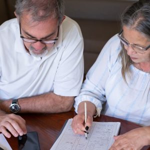 The cost of withdrawing pension cash early can appear years later: an older couple going through pension and retirement paperwork together at home